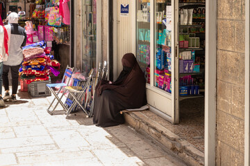 Muslim woman dressed in hijab sits and begs in the Arab quarter in the old city of Jerusalem, Israel