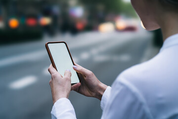 Cropped view of female fingers chatting online in social networks on blank display of modern smartphone using 4g internet on blurred background.Female blogger making payment on website on telephone