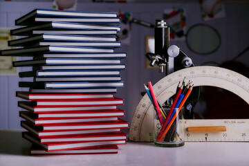 concept of red and blue books which lie on top of each other. Multicolored pencils and school subjects on the background.