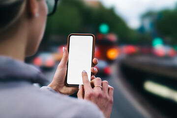 Cropped back view of woman's hands holding smartphone and typing with finger on blank screen of gadget using 4G internet connection to installing app.Digital mobile phone with copy space area