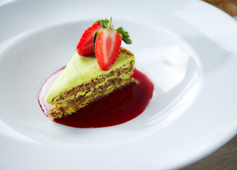 Pistachio puff cake with strawberries in a white plate. Close-up
