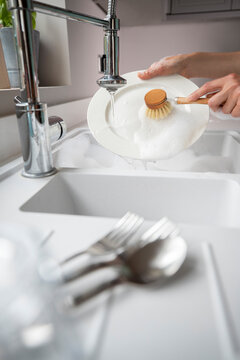 Woman Washing Up At Home Using Eco Dish Brush For Sustainable Lifestyle