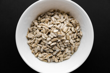 Sunflower seeds in a small plate on the black table. Healthy vegetarian protein nutritious food.