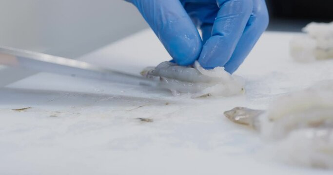 Professional chef peeling shrimps, snocking skin with knife