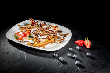 Traditional Belgian dessert - waffle with strawberry and cream on a dark background