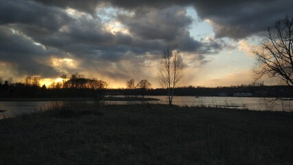Spring sunset with sky clouds river earth