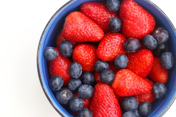Bowl of blueberries and strawberries on white background. Top view.