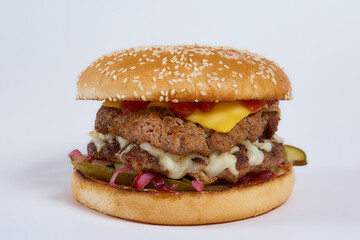 Juicy burger with cucumbers, lettuce, cheese on a white background