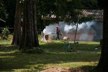 People spray mosquitoes with a spray machine that produces white smoke.