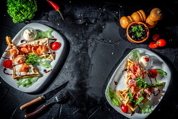 Belgian waffles with prosciutto, salmon and vegetable on dark background