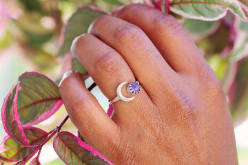 Hand wearing decorative beautiful ring and touching spring plant