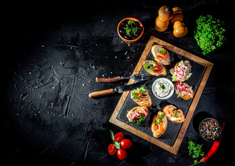 Bruschetta with tomatoes, mozzarella cheese and basil on dark background. Traditional italian appetizer or snack, antipasto