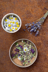 scrub of natural ingredients in indian bowl, vessel with water,   lavander and chamomile   flowers