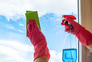 Washing windows. A cleaner in pink rubber gloves pokes a wiper onto the glass and wipes it with a green rag