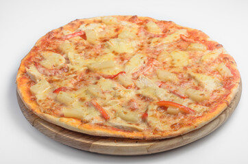 Pizza with chicken and pineapple. Lies on a wooden board on a white background