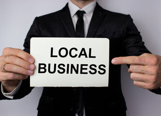 Local business inscription in black letters on a white sheet of paper in the hands of a businessman. Local business support concept.