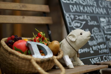 A basket with vegetables and a piglet figurine displayed in front of a fashionable shop