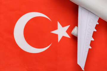 Travel concept. Passenger plane wing against the background of Turkish flag
