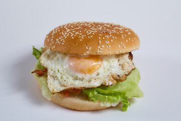 Juicy burger with cucumbers, lettuce, cheese on a white background