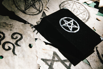 Occult grimoire, magic book laying on table with occult symbols, candles, pentagrams, fortune...