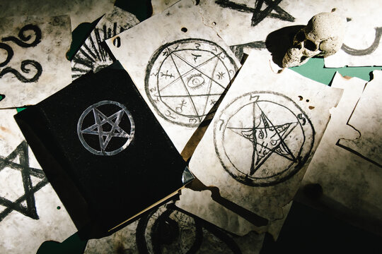 Occult grimoire, magic book laying on table with occult symbols, candles, pentagrams, fortune telling, ritual, altar, spiritism, secret knowledge, scull