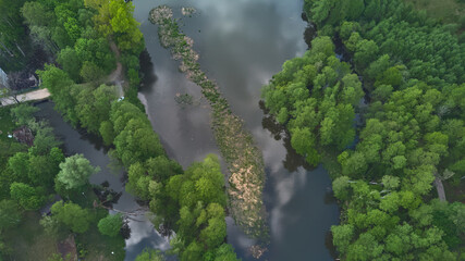 Aerial vertical view of a river surrounded by trees. Late spring in Poland Eastern Europe.