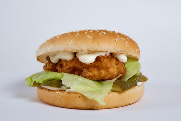 Juicy burger with cucumbers, lettuce, cheese on a white background