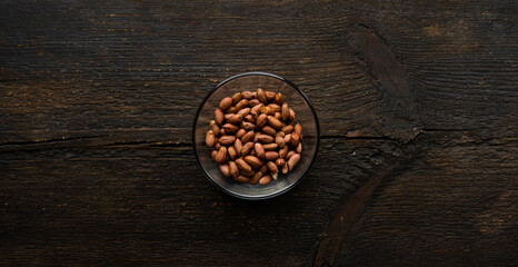 Peanut nuts in a small plate on a vintage wooden table. Peanuts nut is a healthy vegetarian protein nutritious food.