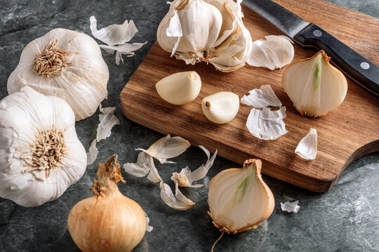 Peeling garlic cloves and bulbs on a dark stone board and old wooden cutting board. top view.