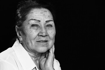 Close-up black and white portrait of an elderly senior Asian woman, smiling when thinking about her life