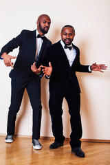 two afro-american businessmen in black suits emotional posing, gesturing, smiling. wearing bow-ties entertaiment stuff