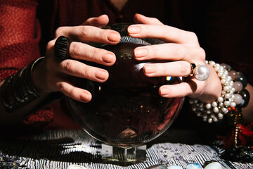 Closeup of fortuneteller's hands on a glass orb. Prediction of the future. Mystic interior