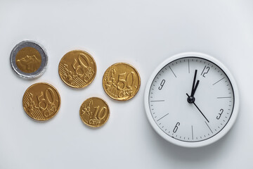Time is money. White clock with  coins on white background. Top view