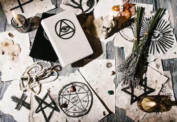 White magic book laying on the table with old manuscripts with occult symbols, candles, lavender....