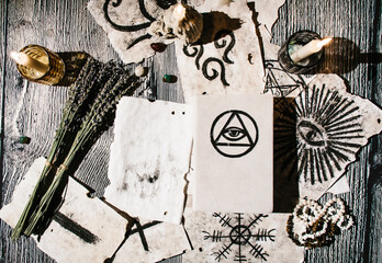 White magic book laying on the table with old manuscripts with occult symbols, candles, lavender. Concept of fortune telling, ritual, altar, spiritism, secret knowledge