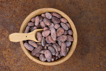 Cocoa flat lay  concept with raw cocoa beans in woooden bowl and spoon on iron  background,