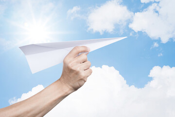 Hand holding white paper airplane rocket on cloud blue sky background success goal business concept