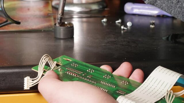 Close up of man's hands soldering microswitch electrical card using slodering iron.