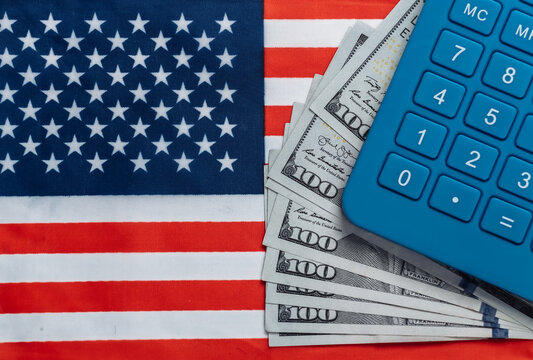 Calculator with hundred dollar bills on background of USA flag - Powered by Adobe
