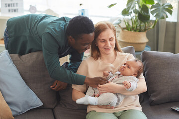 Warm-toned portrait of happy interracial family enjoying time together at home, with...