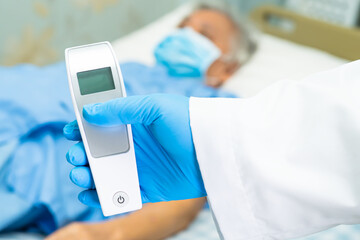 Doctor holding digital thermometer to measures asian senior or elderly old lady woman patient wearing a face mask have a fever in hospital : healthy strong medical concept.