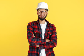 Attractive bearded engineer or constructor man in plai shirt standing over yellow background. Looking in camera. - obrazy, fototapety, plakaty