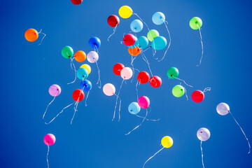 Many multicolored helium balloons fly into the sky
