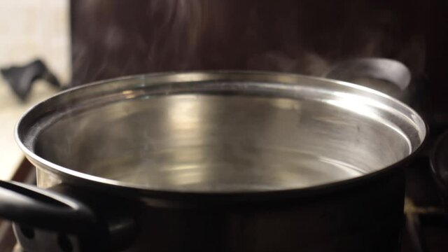 steam rises from a pan with water close-up, blurred background