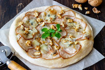 Pizza with pear, gorgonzola cheese, nuts, honey and mint. Healthy eating. Vegetarian food. Recipe.