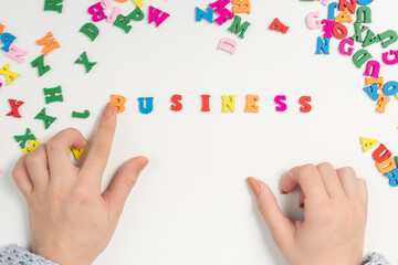 The concept of opening a company from scratch. Female hands lay out the word business from multi-colored letters