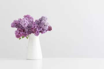 Schilderijen op glas Bouquet of lilac flowers in a vase on a white table with blank copy space. © Snoflinga