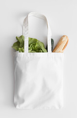 White tote bag mockup with groceries on a white table.