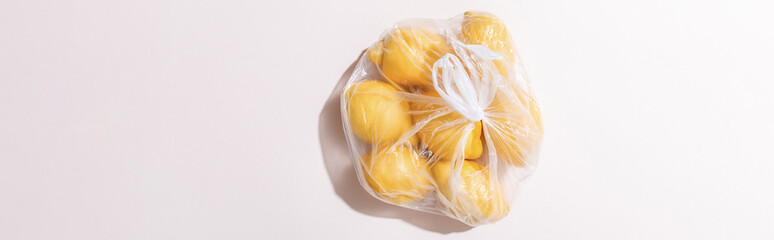 top view of yellow lemons in plastic bag on grey table, horizontal crop