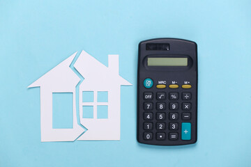 Divorce, property division concept. Split paper house and calculator on blue background